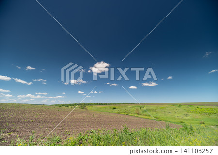 Wide rural field under blue sky with scattered clouds 141103257