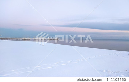 A winter landscape of a snowy beach leading to a jetty A winter landscape of a snowy beach leading to a jetty 141103360