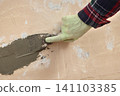Worker spreading plaster to damaged wall Worker spreading plaster to damaged wall 141103385