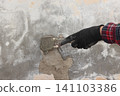 Worker spreading plaster to damaged wall Worker spreading plaster to damaged wall 141103386