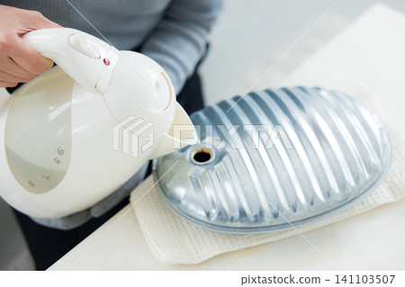 woman using hot water bottle woman using hot water bottle 141103507