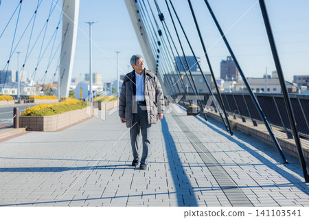 一位六十多歲的男子穿著外套行走。 一位六十多歲的男子穿著外套行走。 141103541