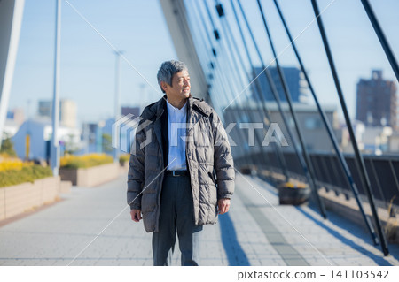 一位六十多歲的男子穿著外套行走。 一位六十多歲的男子穿著外套行走。 141103542