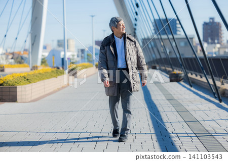 一位六十多歲的男子穿著外套行走。 一位六十多歲的男子穿著外套行走。 141103543