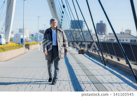 一位六十多歲的男子穿著外套行走。 一位六十多歲的男子穿著外套行走。 141103545