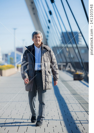 一位六十多歲的男子穿著外套行走。 一位六十多歲的男子穿著外套行走。 141103548