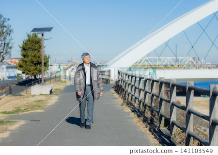一位六十多歲的男子穿著外套行走。 一位六十多歲的男子穿著外套行走。 141103549