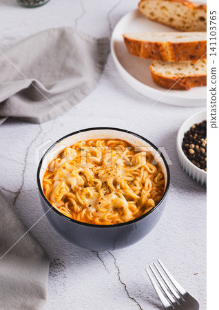 Delicious cheesy spicy ramen noodles in a bowl on the table vertical view Delicious cheesy spicy ramen noodles in a bowl on the table vertical view 141103765