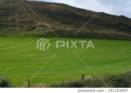 Green grass smooth even golf course field among the hills in France. Professional sport and hobby, entrtainment during traveling or vacations. Grassy surface maintenance Green grass smooth even golf course field among the hills in France. Professional sport and hobby, entrtainment during traveling or vacations. Grassy surface maintenance 141103997