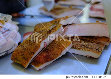 market pork lard. Stack of thick sliced cured pork belly with visible fat layers and rind texture arranged for sale as traditional spanish food product in local market setting market pork lard. Stack of thick sliced cured pork belly with visible fat layers and rind texture arranged for sale as traditional spanish food product in local market setting 141104049