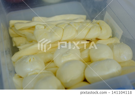 Fresh suluguni and braided mozzarella cheese in container at farmer market traditional handmade dairy products Fresh suluguni and braided mozzarella cheese in container at farmer market traditional handmade dairy products 141104118