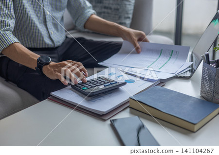 Male Entrepreneur or Remote Worker Calculating Budget and Analyzing Documents at Home Office Couch. Male Entrepreneur or Remote Worker Calculating Budget and Analyzing Documents at Home Office Couch. 141104267