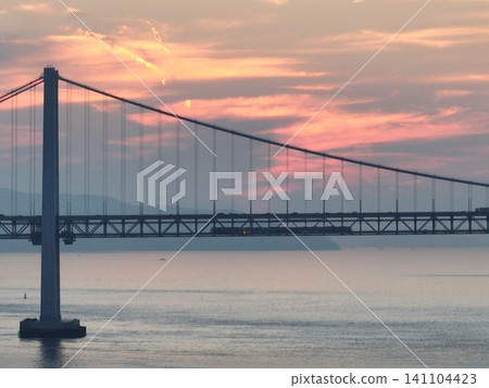 A train crossing the Kita-Bisan Seto Bridge at sunset. 141104423