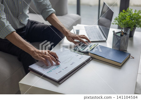 Man working on financial reports and business data analytics at home office. Man working on financial reports and business data analytics at home office. 141104584