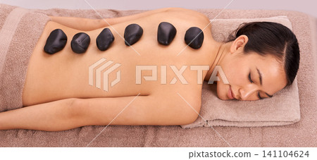 Calm, hot stone and woman with back massage at spa for wellness, self care and grooming treatment for healing. Skin, girl and high angle of person with warm rock body routine on table for zen. Calm, hot stone and woman with back massage at spa for wellness, self care and grooming treatment for healing. Skin, girl and high angle of person with warm rock body routine on table for zen. 141104624