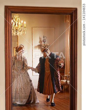 Renaissance, man and woman holding hands in royal castle together with vintage love, romance and banquet. Medieval king, queen or couple in ballroom for happy dance performance in palace in Europe Renaissance, man and woman holding hands in royal castle together with vintage love, romance and banquet. Medieval king, queen or couple in ballroom for happy dance performance in palace in Europe 141104653