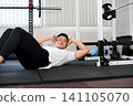 A young Asian man doing sit-ups at the gym. 141105070