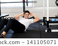 A young Asian man doing sit-ups at the gym. 141105071
