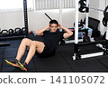 A young Asian man doing sit-ups at the gym. 141105072