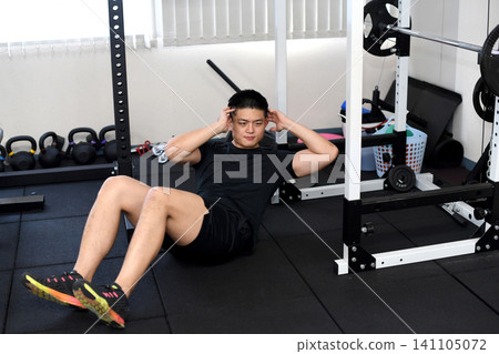 A young Asian man doing sit-ups at the gym. A young Asian man doing sit-ups at the gym. 141105072