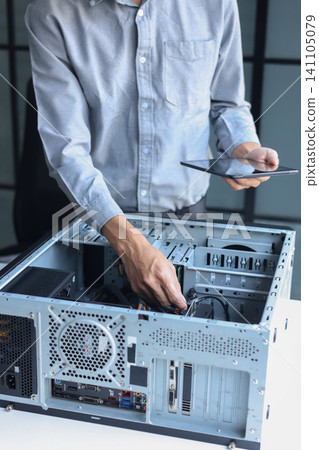 IT technician using tablet while repairing computer motherboard and computer hardware components. IT technician using tablet while repairing computer motherboard and computer hardware components. 141105079