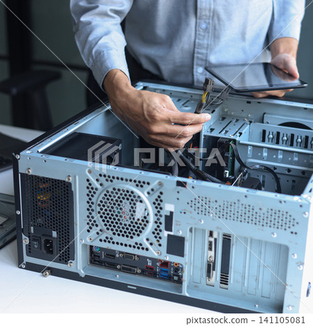 IT technician using tablet while repairing computer motherboard and computer hardware components. IT technician using tablet while repairing computer motherboard and computer hardware components. 141105081
