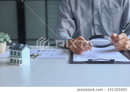 Close-up of home inspector reviewing property purchase agreement with magnifying glass. Close-up of home inspector reviewing property purchase agreement with magnifying glass. 141105083