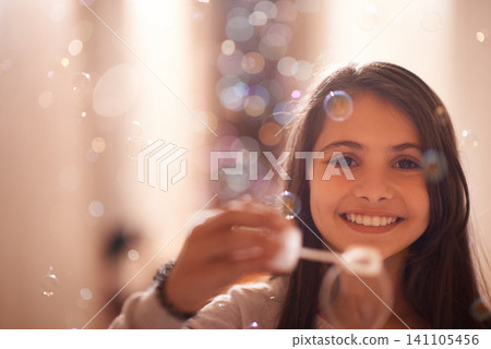 Home, happy and portrait of child with bubbles for relaxing, resting and playing in bedroom. Youth, smile and face of young girl with soap bubble for childhood memory, playful and happiness in house Home, happy and portrait of child with bubbles for relaxing, resting and playing in bedroom. Youth, smile and face of young girl with soap bubble for childhood memory, playful and happiness in house 141105456