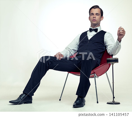 Fashion, gentleman and portrait with tuxedo and cigarette for stylish, trend and habit with suit and luxury. Young person and sit with confidence for vintage, wealthy and handsome for rich on mockup Fashion, gentleman and portrait with tuxedo and cigarette for stylish, trend and habit with suit and luxury. Young person and sit with confidence for vintage, wealthy and handsome for rich on mockup 141105457