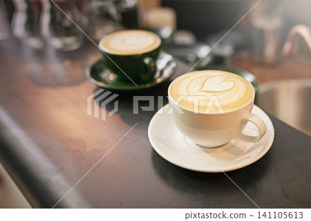 Coffee on counter, cup and latte with art for creativity, cappuccino or caffeine drink with pattern. Warm beverage on table, foam and milk with heart or leaf design, hospitality and service at cafe Coffee on counter, cup and latte with art for creativity, cappuccino or caffeine drink with pattern. Warm beverage on table, foam and milk with heart or leaf design, hospitality and service at cafe 141105613