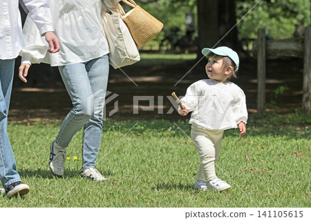 一對年輕的父母帶著一個小孩散步。 一對年輕的父母帶著一個小孩散步。 141105615