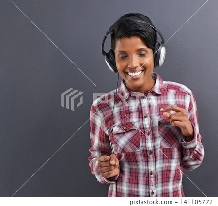 Happy woman, dancing and listening with headphones for music or podcast on a gray studio background. Young female person or Indian with smile, enjoying audio sound track with headset on mockup space Happy woman, dancing and listening with headphones for music or podcast on a gray studio background. Young female person or Indian with smile, enjoying audio sound track with headset on mockup space 141105772
