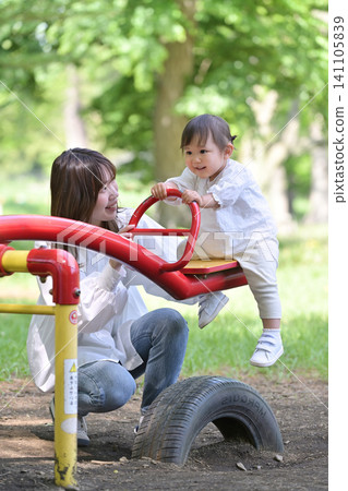 A mother and daughter enjoying a seesaw in the park. 141105839