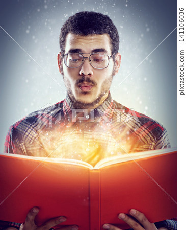 Thinking, glowing book and man with story, fantasy and education on grey studio background. Person, model and guy with novel and literature with knowledge and learning with light, creative or magic 141106036
