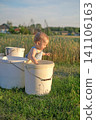 A small child splashing in a bucket of water in the garden. Children's pranks.  141106163