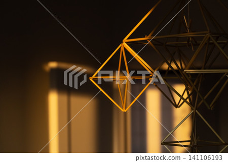 Geometric wooden hanging decoration illuminated by warm golden hour sunlight Geometric wooden hanging decoration illuminated by warm golden hour sunlight 141106193
