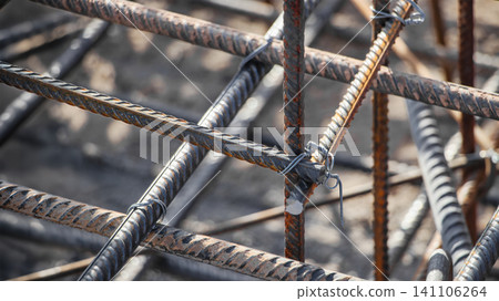 Workers prepare a reinforcement cage for a concrete foundation at a construction site. Steel bars are tied together to form a strong framework before pouring concrete Workers prepare a reinforcement cage for a concrete foundation at a construction site. Steel bars are tied together to form a strong framework before pouring concrete 141106264