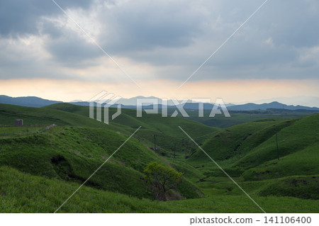 A view of the orange sky and gently rolling hills from the Aso Milk Road at dusk - Kumamoto Prefecture A view of the orange sky and gently rolling hills from the Aso Milk Road at dusk - Kumamoto Prefecture 141106400