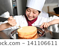 An image of an Asian female pastry chef finishing a cake. 141106611