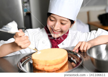 An image of an Asian female pastry chef finishing a cake. An image of an Asian female pastry chef finishing a cake. 141106611