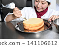 An image of an Asian female pastry chef finishing a cake. 141106612