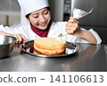 An image of an Asian female pastry chef finishing a cake. 141106613