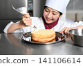 An image of an Asian female pastry chef finishing a cake. 141106614