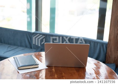 Modern workplace with laptop notebook and documents on wooden table in cafe office Modern workplace with laptop notebook and documents on wooden table in cafe office 141107556