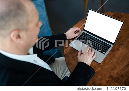 Businessman working on laptop at cafe table. 141107870