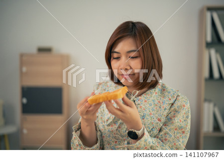 Young woman holding slice of bread indoors focusing on food detail Young woman holding slice of bread indoors focusing on food detail 141107967