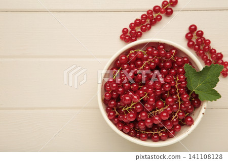 Red currants on white plate on light wooden background. Fresh and vibrant food photography for healthy eating. Red currants on white plate on light wooden background. Fresh and vibrant food photography for healthy eating. 141108128