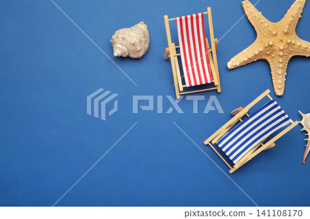 Summer beach flat lay. Two miniature deck chairs with seashells, starfish on dark blue background. Space for text Summer beach flat lay. Two miniature deck chairs with seashells, starfish on dark blue background. Space for text 141108170