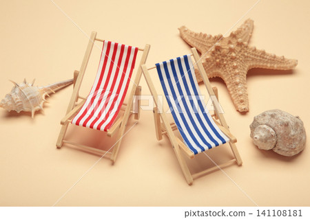 Summer beach flat lay. Two miniature deck chairs with seashells, starfish on beige background 141108181