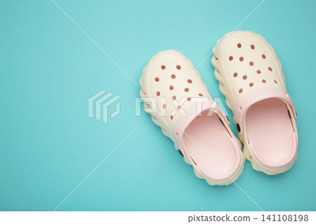 Mykolaiv, Ukraine - April 25, 2026: Couple of white Crocs sandals on light blue background. Mykolaiv, Ukraine - April 25, 2026: Couple of white Crocs sandals on light blue background. 141108198
